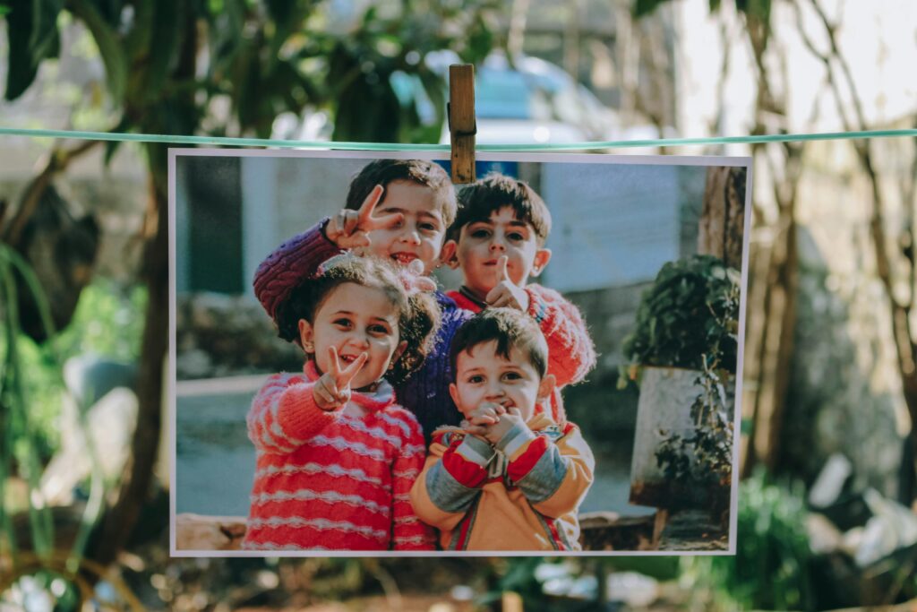 Four smiling children gesture peace signs while posing for a photograph.